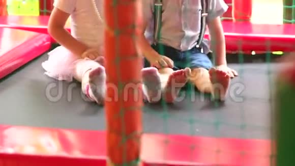 两个小孩子坐在蹦床上弹跳视频的预览图