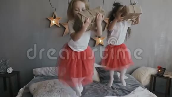 两个小妹妹玩得很开心跳上床手里拿着圣诞礼物在灰色的墙上挂着视频的预览图