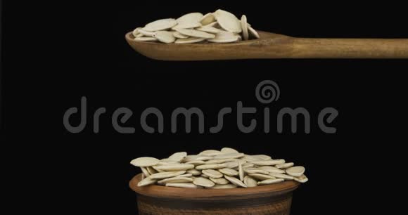 南瓜粒从一个木勺上得到足够的睡眠在一堆泥土碗里的种子上视频的预览图