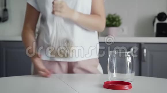 将女士的燕麦片倒入玻璃罐中储存视频的预览图