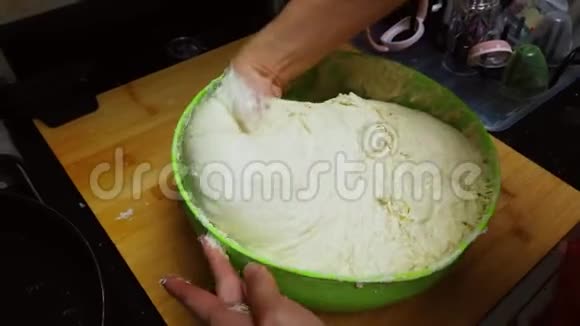 年轻的女人在家里用绿色的碗揉面包面团隔离或隔离的人们自己做面包的概念视频的预览图