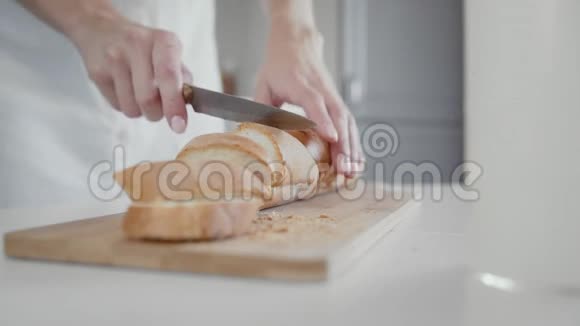 一个年轻的女人用一把面包刀切一条面包视频的预览图