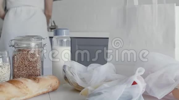 在厨房的木桌上把装有面包燕麦片荞麦牛奶蔬菜和水果的未包装购物袋关上视频的预览图