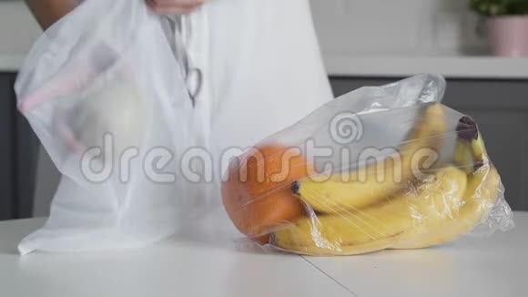 年轻的女人把水果从塑料袋移到厨房木桌上可重复使用的网袋零废物之家和生态袋视频的预览图