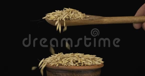 燕麦颗粒从一个木勺上得到足够的睡眠在一堆泥土碗里的种子视频的预览图