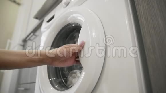 女性的手试图打开洗衣机并采取白色的颜色去装洗衣机把衣服装上洗衣机视频的预览图