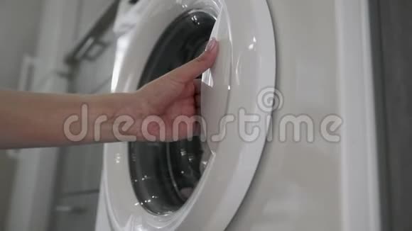 带结婚戒指的女性手从洗衣机里拿着绿色的衣服去装洗衣机把衣服装上洗衣机视频的预览图