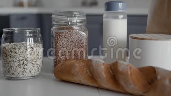 厨房的木桌上放着面包荞麦燕麦片牛奶和蔬菜的未包装购物袋零视频的预览图