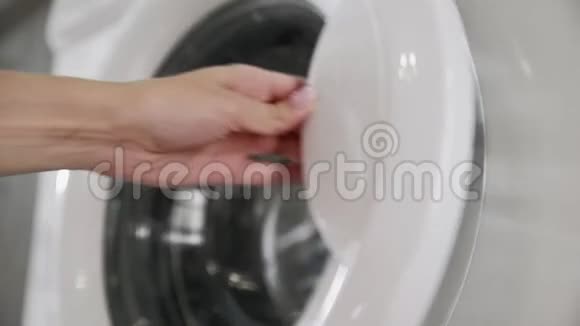 带结婚戒指的女性手从洗衣机里拿出粉红色的衣服去装洗衣机把衣服装上洗衣机视频的预览图