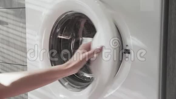 女性手把粉红色的衣服放在洗衣机里去装洗衣机把衣服装进洗衣机穿上衣服视频的预览图