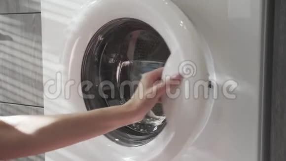 女性手把粉红色的衣服放在洗衣机里去装洗衣机把衣服装进洗衣机穿上衣服视频的预览图