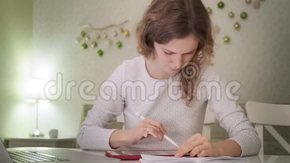 一个年轻的女人在家里的电脑平板电脑上工作视频的预览图