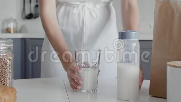 接近无法辨认的女人穿着白色连衣裙在桌子上喝牛奶玻璃作为早餐视频的预览图