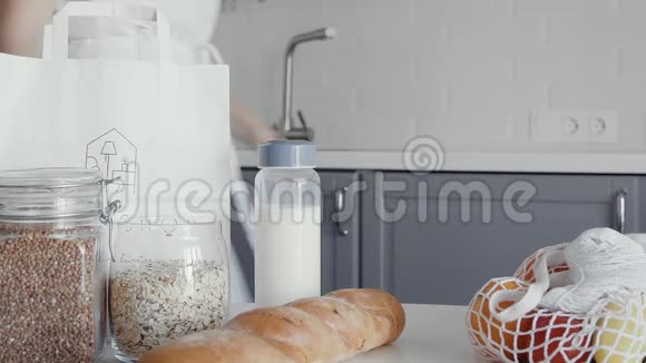 金发女人把面包燕麦片牛奶蔬菜从桌子上移到架子上零废家和生态袋生态视频的预览图