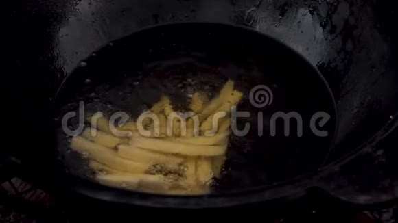 一个女人把土豆扔进一锅沸腾的油里切片土豆沸腾在油特写慢慢地视频的预览图