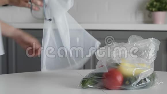 年轻女子将蔬菜从塑料袋移到厨房木桌上可重复使用的网袋零废物视频的预览图