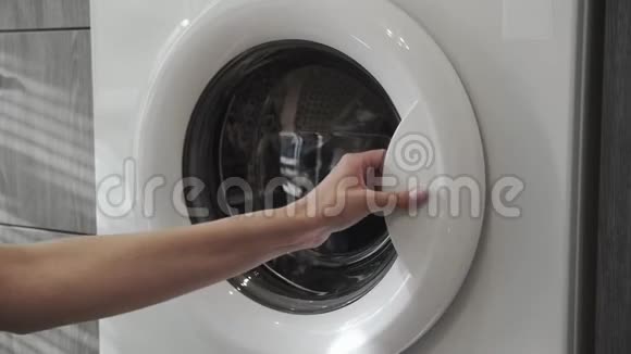 女性手从洗衣机里拿黑色的衣服去装洗衣机把衣服装进洗衣机负荷视频的预览图