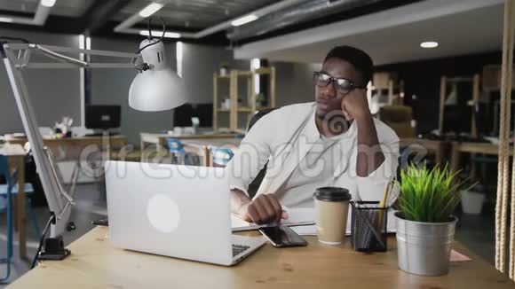 疲惫的非洲男人正在看电话等着下班视频的预览图