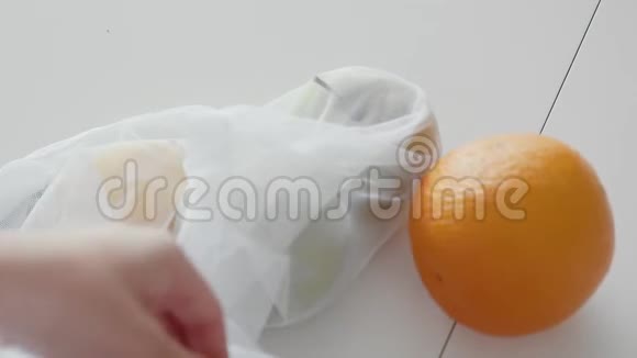 在木桌上的厨房里用苹果橘子和柠檬把女人打开的网状购物袋合上零废物视频的预览图