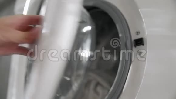 带结婚戒指的女性手从洗衣机里取出粉红色的衣服去装洗衣机把衣服装上洗衣机视频的预览图