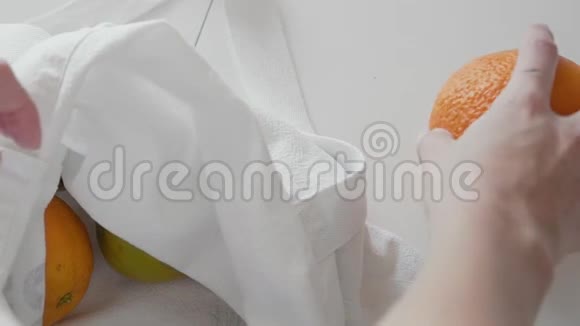 在木桌上的厨房里用苹果橘子和柠檬把女人拆包的布料购物袋合上零视频的预览图