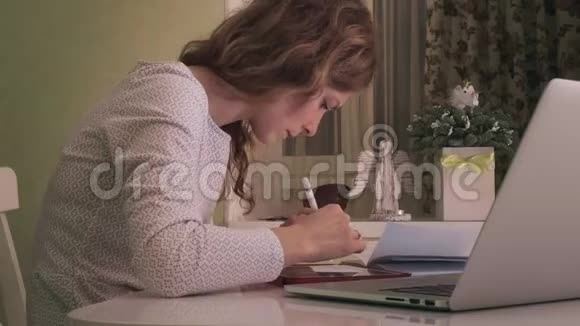 一个年轻的女人在家里的电脑平板电脑上工作视频的预览图