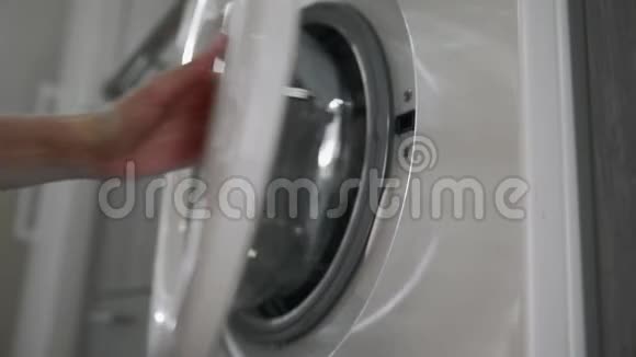 带结婚戒指的女性手从洗衣机里拿出粉红色的衣服去装洗衣机把衣服装上洗衣机视频的预览图