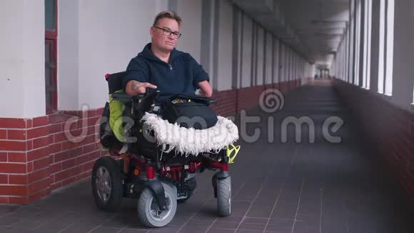 坐在轮椅上的残疾妇女在办公室走廊里使用智能手机视频的预览图