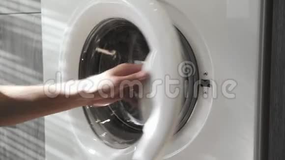 结婚戒指的男性手把JEANS放进洗衣机里去装洗衣机把衣服装进洗衣机负荷视频的预览图