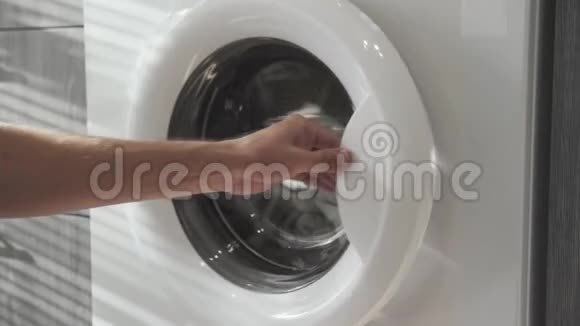 男性手把绿色的衣服放在洗衣机里去装洗衣机把衣服装进洗衣机穿上衣服视频的预览图