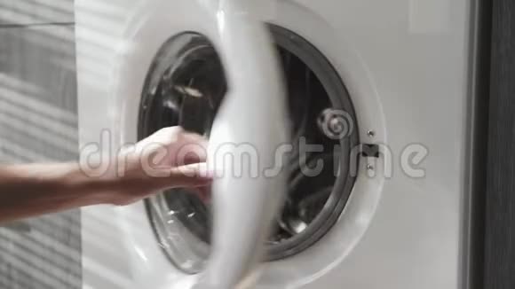 带结婚戒指的男性手在洗衣机里放颜色去装洗衣机把衣服装上洗衣机视频的预览图
