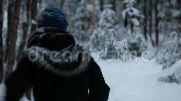 冬天独自在森林里散步和徒步旅行的女孩视频的预览图