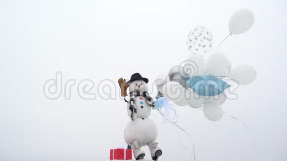 户外雪人真有趣快乐有趣的雪人在白雪背景上拿着气球雪人戴着一顶毛皮帽子视频的预览图