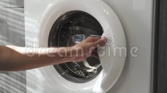 结婚戒指的男性手把黑色的衣服放在洗衣机里去装洗衣机把衣服装上洗衣机视频的预览图
