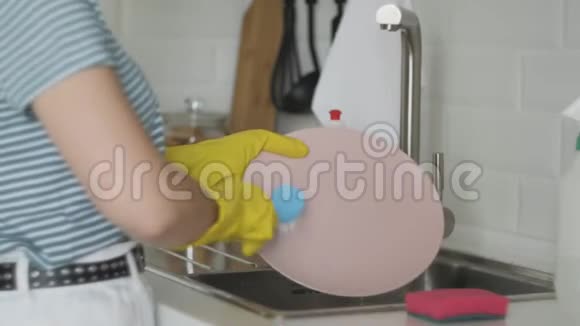 女人的手在厨房水槽里冲洗盘子用海绵盘子洗涤剂在家里做家务洗碗视频的预览图