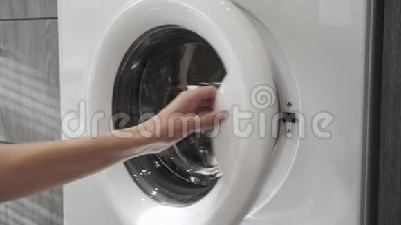 女性手把GREYPANTS放在洗衣机里去装洗衣机把衣服装进洗衣机穿上衣服视频的预览图