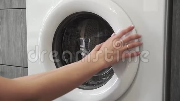 带着结婚戒指的女性手从洗衣机里拿着绿色SWEATER去装洗衣机把衣服装上洗衣机视频的预览图