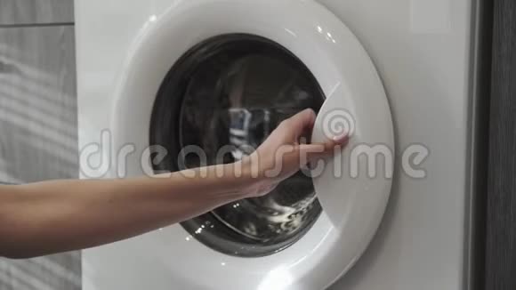 带结婚戒指的女性手把黑色的衣服放进洗衣机里去装洗衣机把衣服装上洗衣机视频的预览图