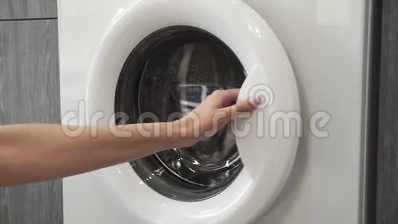 带结婚戒指的女性手把白色手表放在洗衣机里去装洗衣机把衣服装上洗衣机视频的预览图