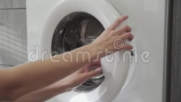女用手拿着洗衣机上的绿色衣服去装洗衣机把衣服装进洗衣机负荷视频的预览图