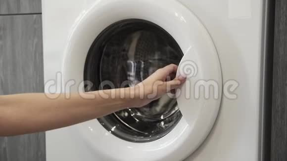 女性手把白色手表放在洗衣机里去装洗衣机把衣服装进洗衣机穿上衣服视频的预览图