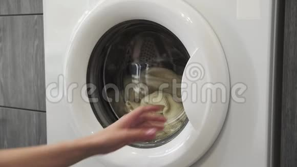 女性手从洗衣机里拿白色SWEATER去装洗衣机把衣服装进洗衣机负荷视频的预览图