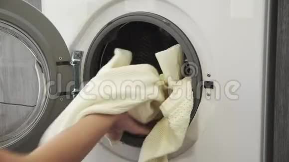 女性手在洗衣机里放两个白色SWEATER去装洗衣机把衣服装进洗衣机负荷视频的预览图