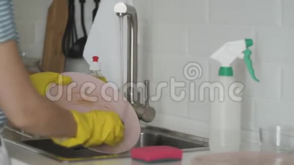 带手套的年轻女子在厨房洗碗视频的预览图