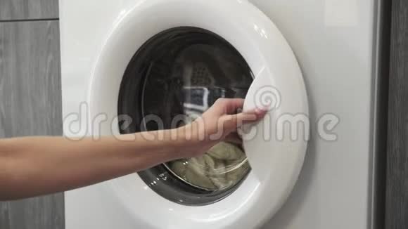 女性手从洗衣机里拿了两个白色SWEATER去装洗衣机把衣服装进洗衣机负荷视频的预览图