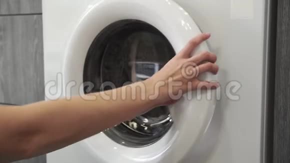 女性手把绿色SWEATER放在洗衣机里去装洗衣机把衣服装进洗衣机穿上衣服视频的预览图