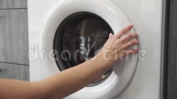 带结婚戒指的女性手从洗衣机里取出彩色衣服去装洗衣机把衣服装上视频的预览图