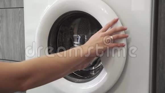 带着结婚戒指的女性手把绿色SWEATER放进洗衣机里去装洗衣机把衣服装上洗衣机视频的预览图