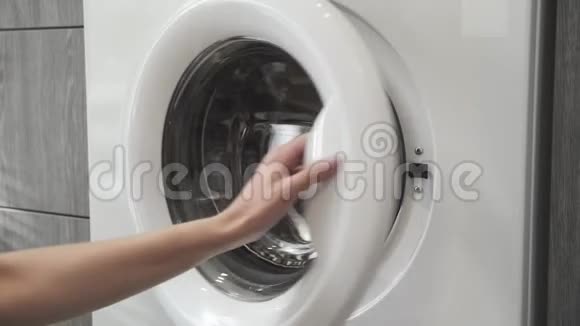 女性手把黑色的衣服放在洗衣机里去装洗衣机把衣服装进洗衣机穿上衣服视频的预览图