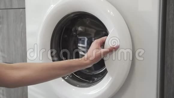 带结婚戒指的女性手从洗衣机里取出白色的衣服去装洗衣机把衣服装上洗衣机视频的预览图